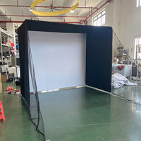 Cage de golf à cadre noir – écran blanc d'impact et filet latéral, vue en atelier