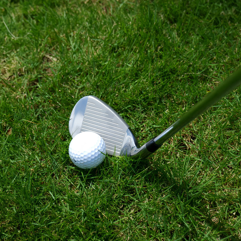 Série de fers de golf – fer posé derrière une balle sur l'herbe