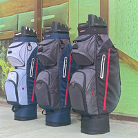 Trois sacs de golf chariot en blanc, bleu marine et gris devant un mur vert