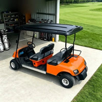 Voiturette de golf 4 places de tourisme – version orange à sièges noirs dans un local de rangement