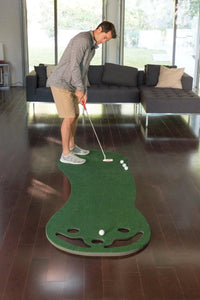 Putting green d'intérieur – golfeur au putting sur le tapis dans un salon