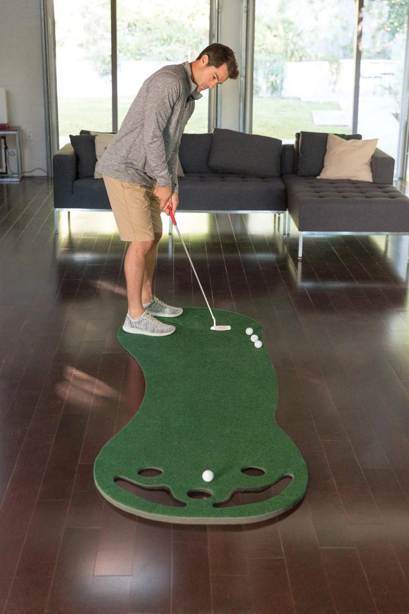Putting green d'intérieur – golfeur au putting sur le tapis dans un salon