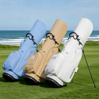 Sac de golf trépied femme – trois sacs bleu ciel, beige et blanc sur un parcours en bord de mer